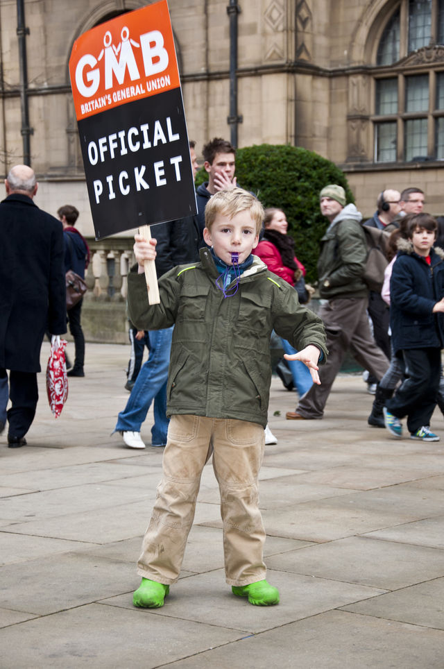 Children waving banners and blowing whistles in support of their parents.